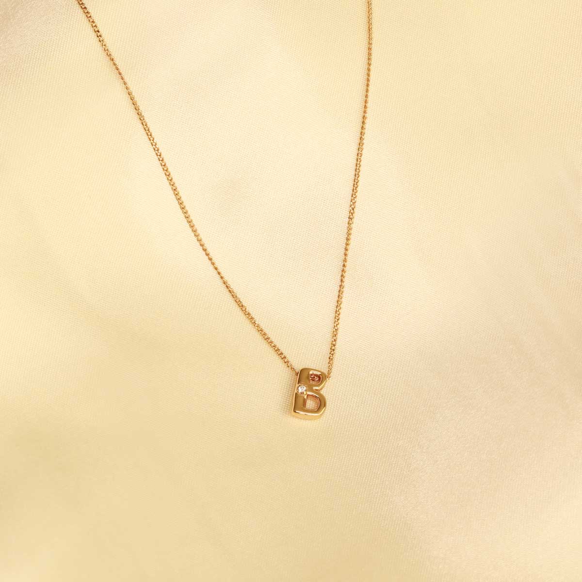 Flat lay shot of B Initial Pendant Necklace in Gold