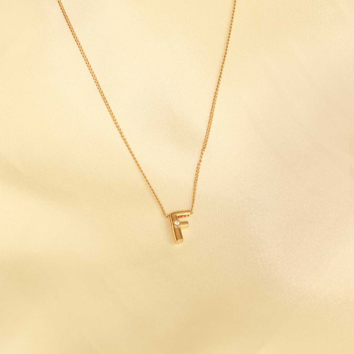 Flat lay shot of F Initial Pendant Necklace in Gold