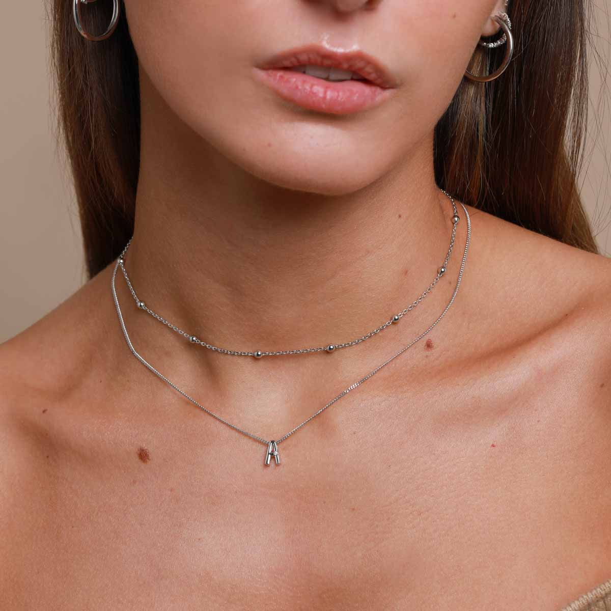 A Initial Pendant Necklace in Silver worn layered with beaded choker necklace