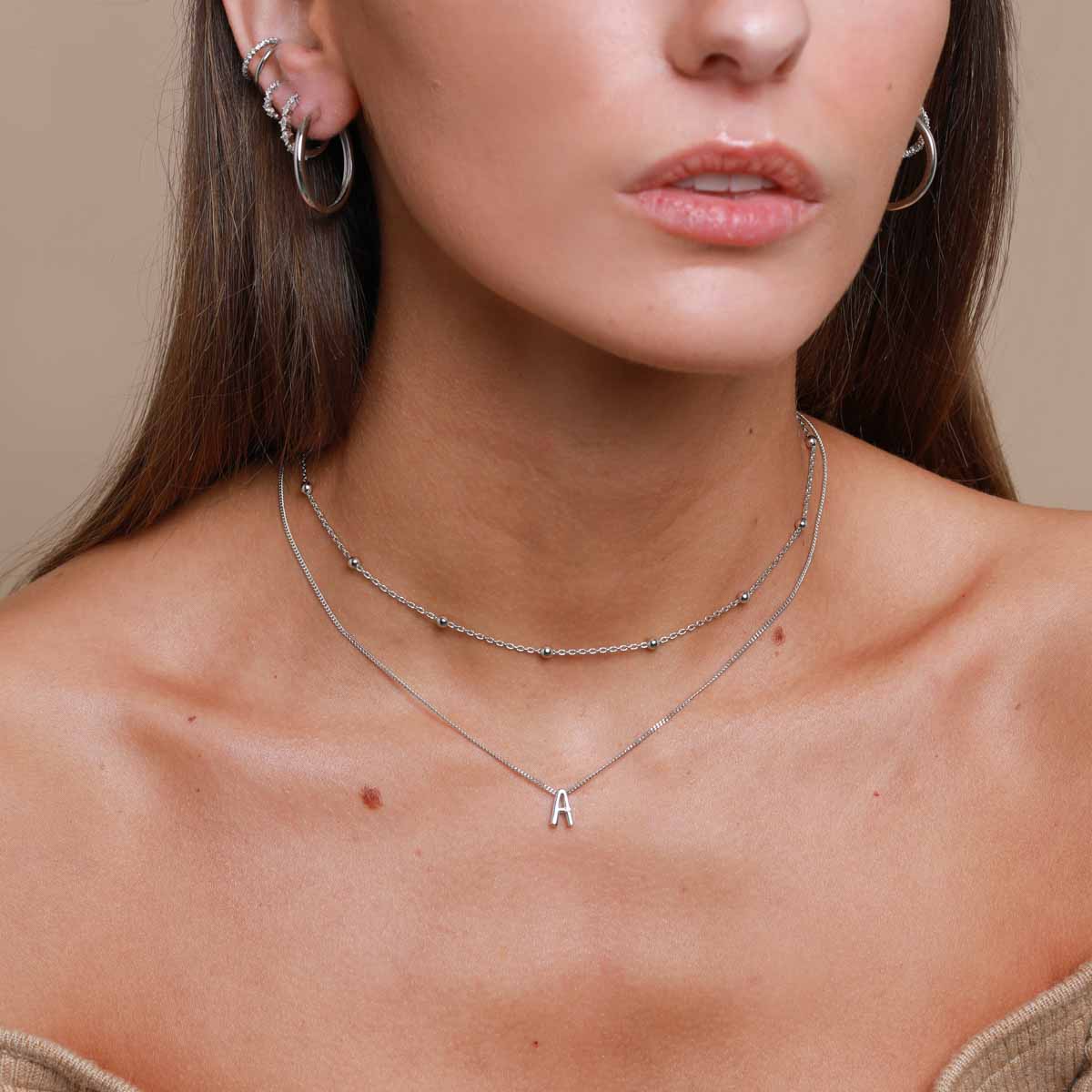 A Initial Pendant Necklace in Silver worn layered with beaded choker necklace