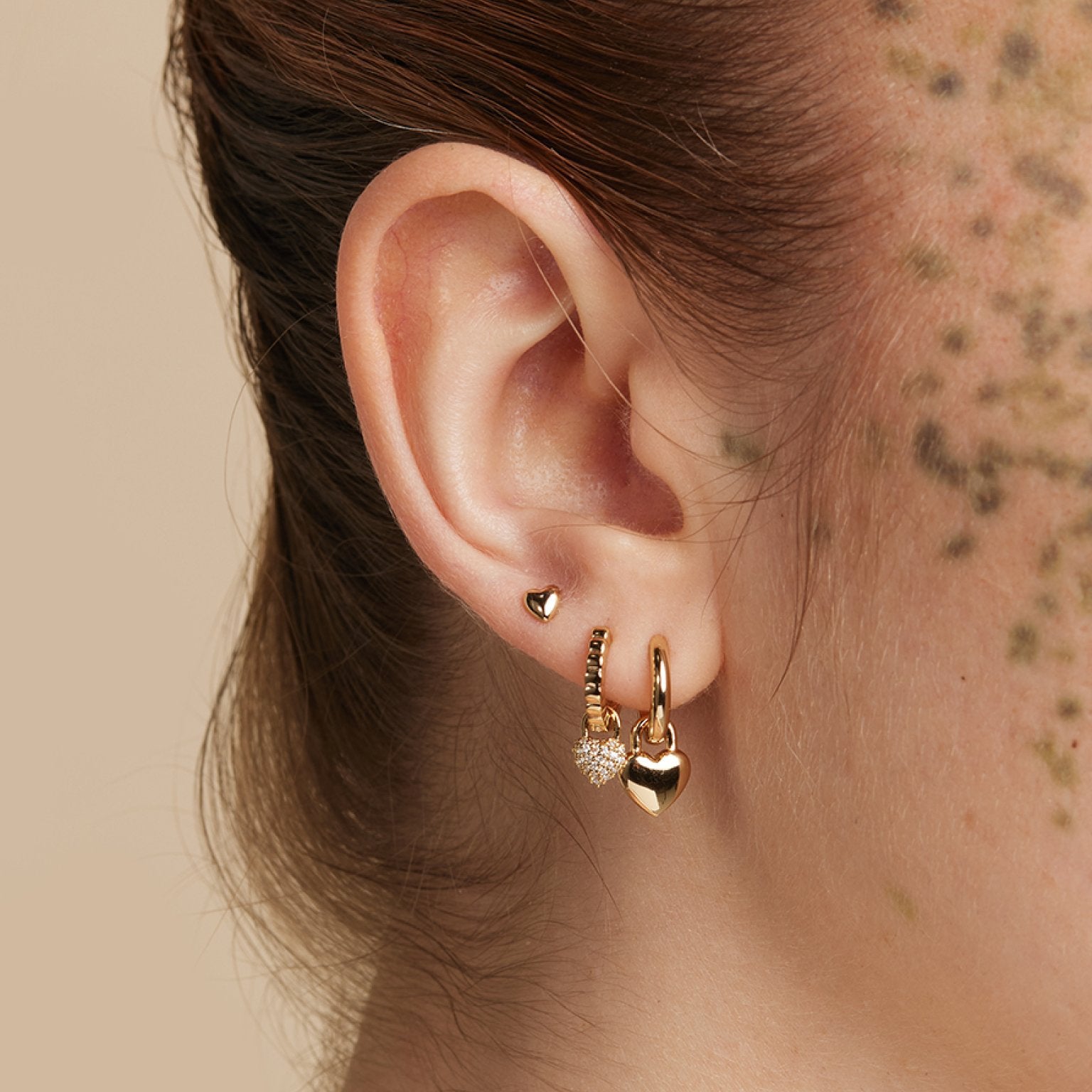 Worn shot of three gold lobe ear jewellery