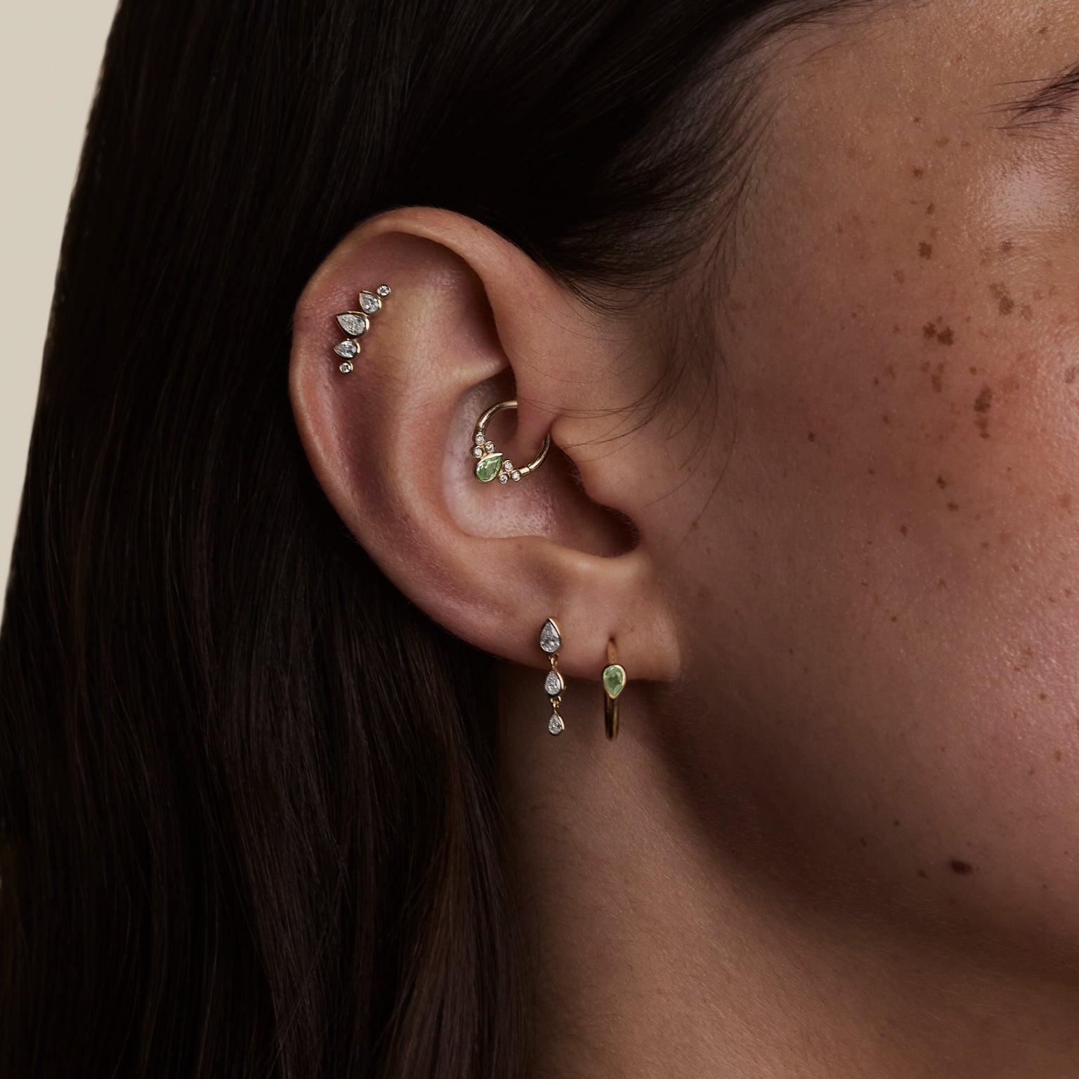 Woman wearing solid gold daith earrings stacked with other solid gold piercing jewellery on her right ear.