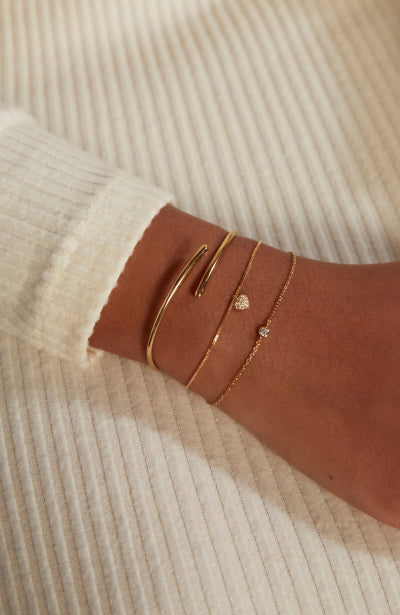 Three elegant gold chain bracelet pieces from Astrid & Miyu worn on a woman's left wrist.