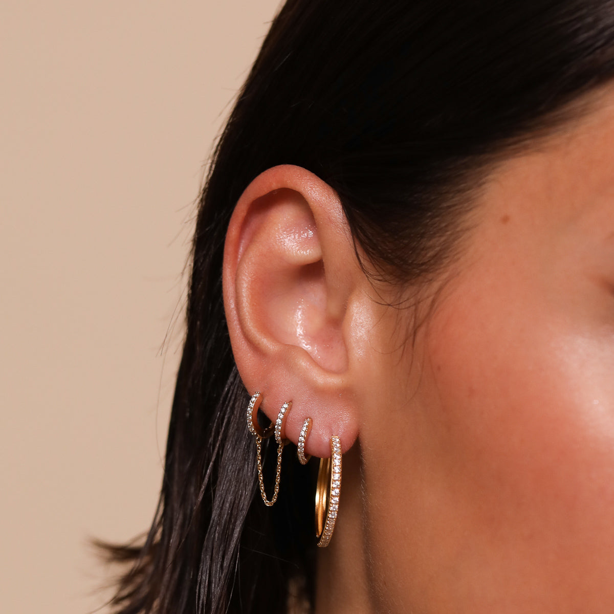 Orbit Crystal Huggies in Gold worn stacked with other earrings