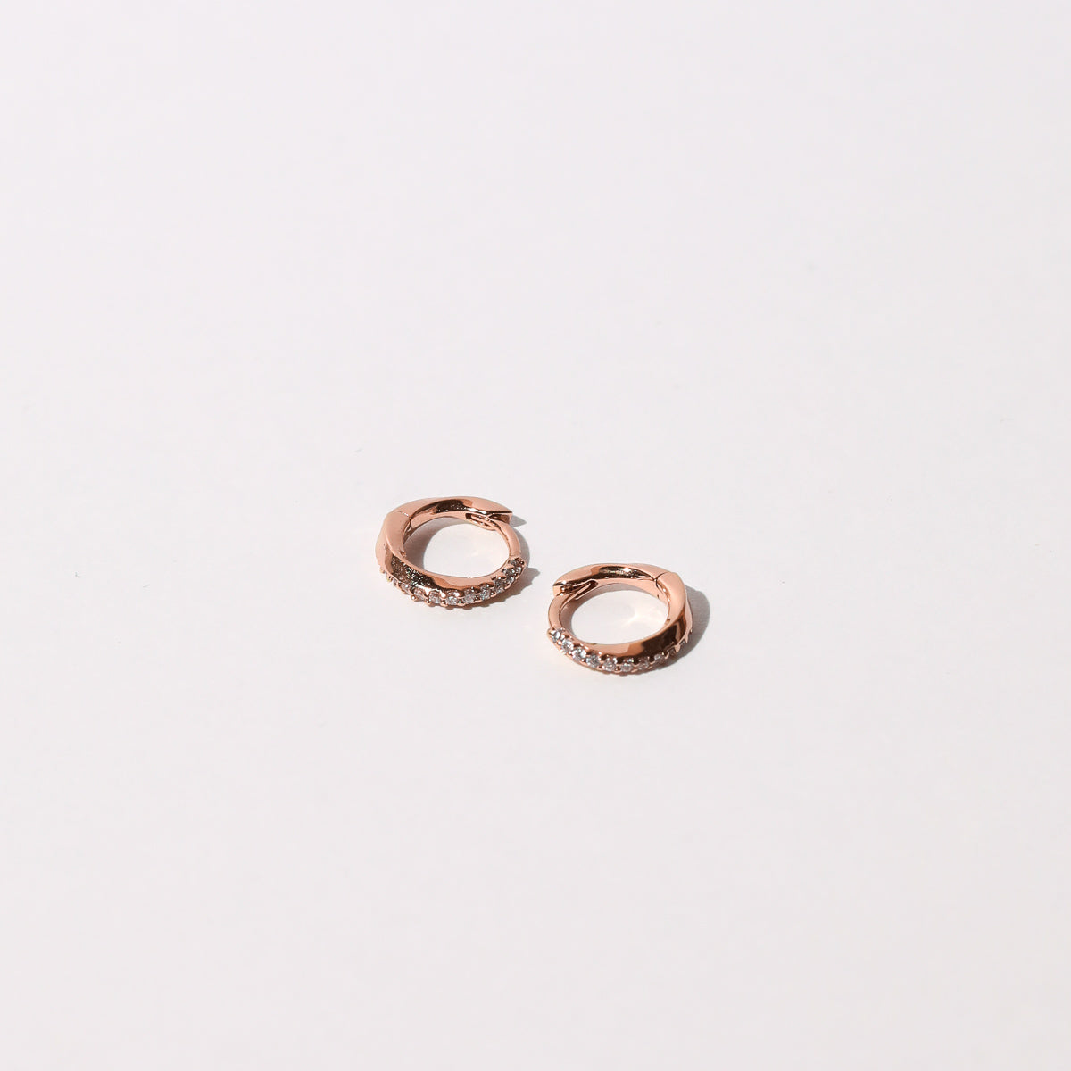Orbit Crystal Huggies in Rose Gold Flat lay