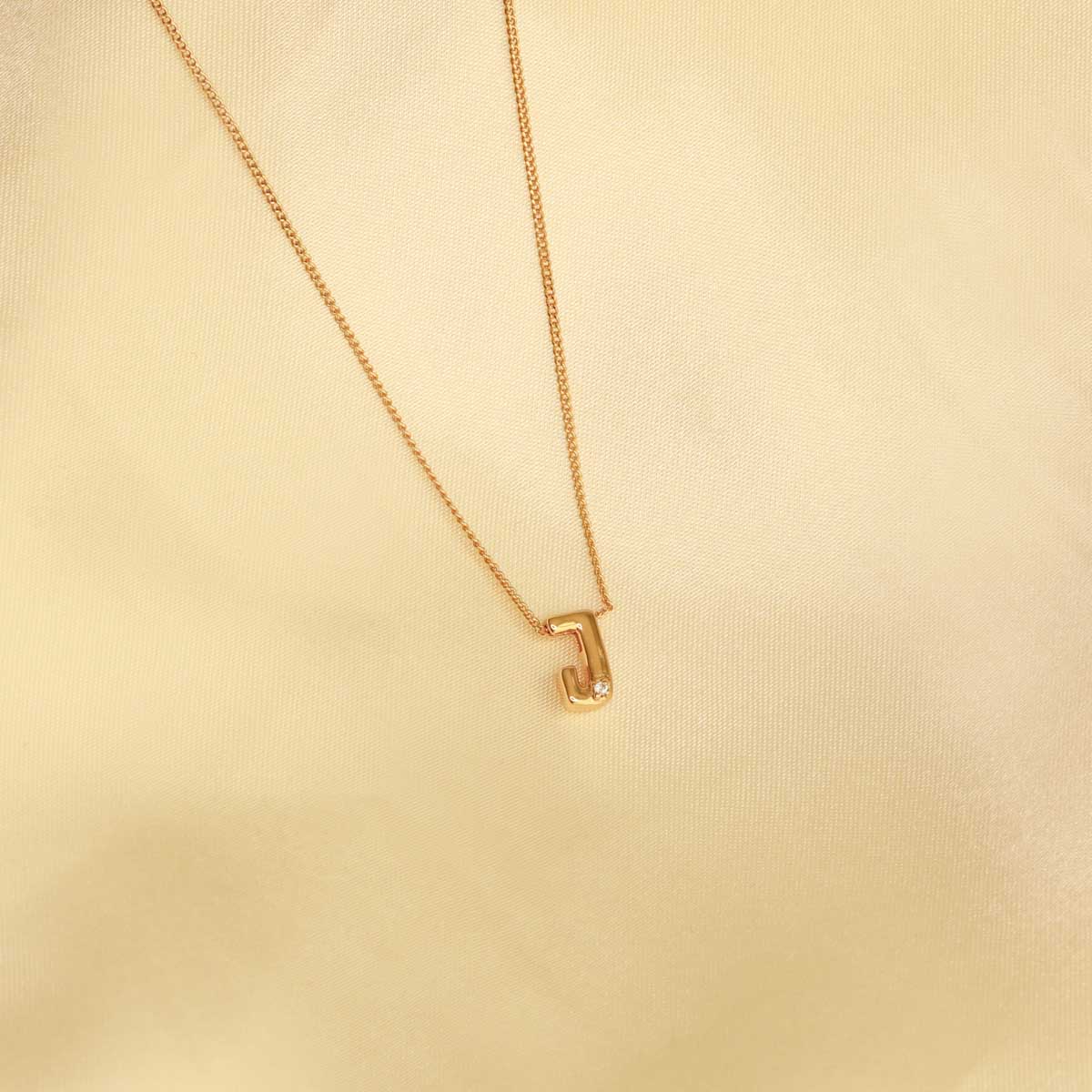 Flat lay shot of J Initial Pendant Necklace in Gold