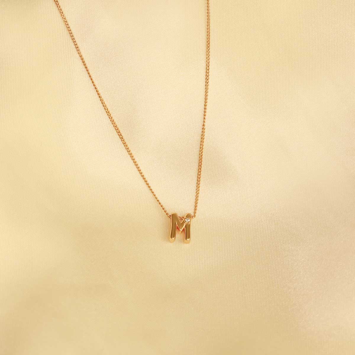 Flat lay shot of M Initial Pendant Necklace in Gold
