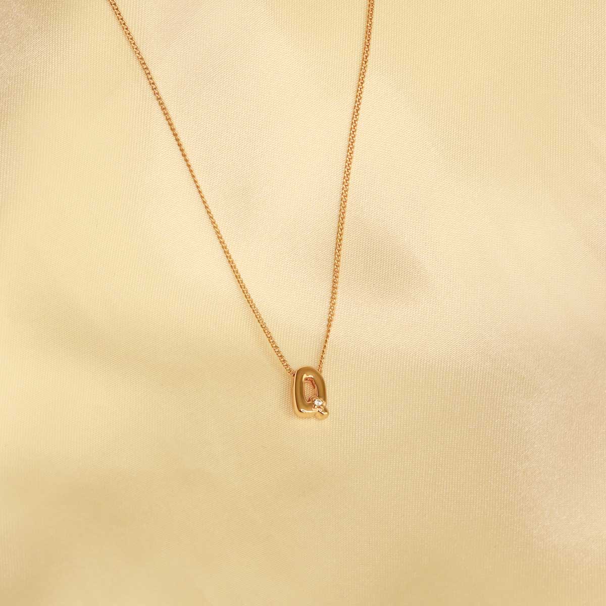 Flat lay shot of Q Initial Pendant Necklace in Gold