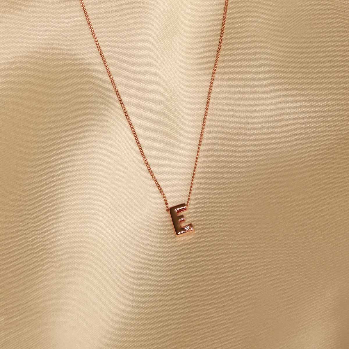 Flat lay shot of E Initial Pendant Necklace in Rose Gold