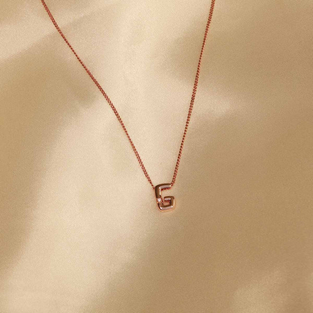 Flat lay shot of G Initial Pendant Necklace in Rose Gold