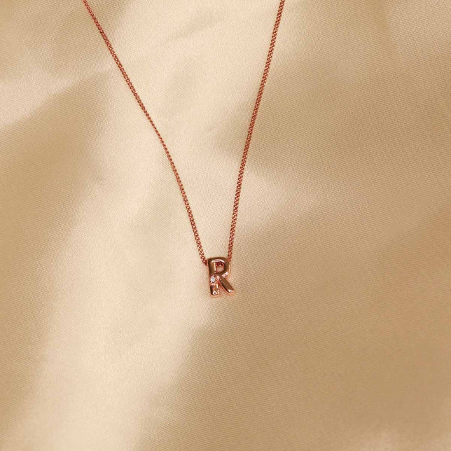 Flat lay shot of R Initial Pendant Necklace in Rose Gold