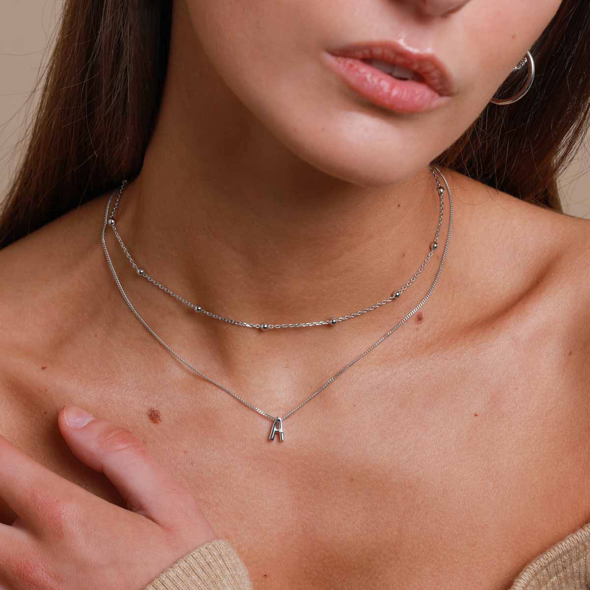 A Initial Pendant Necklace in Silver worn layered with beaded choker necklace