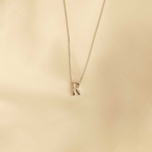 Flat lay shot of R Initial Pendant Necklace in Silver